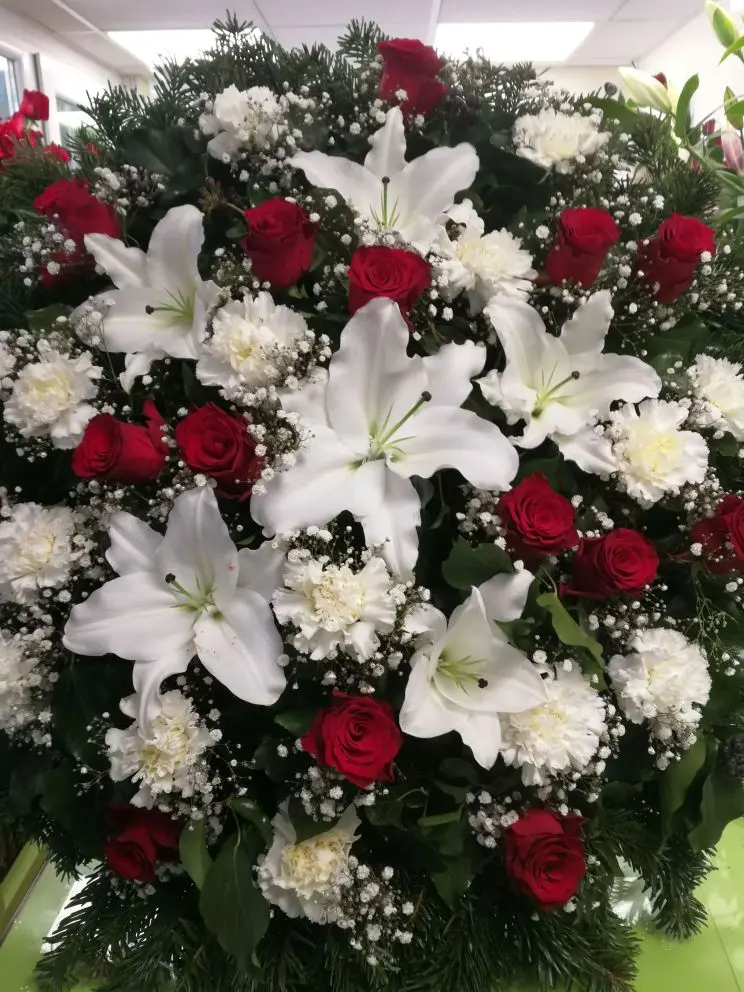 Álló koszorú fehér liliommal, szegfűvel és bordó rózsával, rezgővel – 80–100 cm. Mély tisztelet virágos kifejezése. Nefelejcs Virágüzlet.