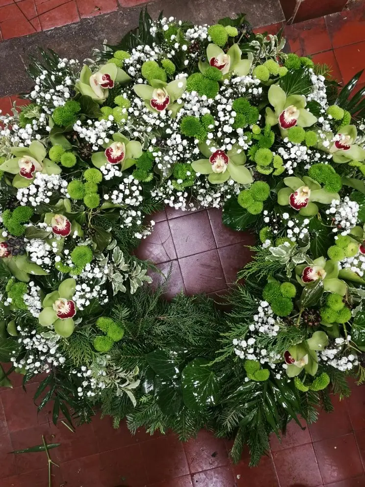 Fekvő görög koszorú zöld orchideával, krizantémmal és fehér rezgővel – fenyő alapon, ~80 cm. Rendelhető több színben. Farkasréti Nefelejcs Virágüzlet.